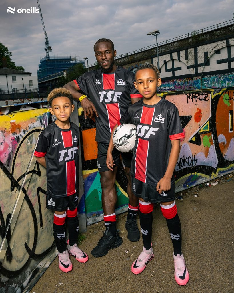 Coach Mali with two young TSF players wearing the black and red O