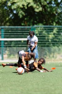 Two under-9 players hitting the deck as they battle for the ball in a 1v1 duel