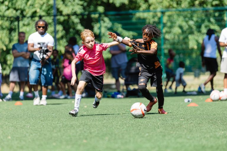 Two young players racing for the ball on the pitch